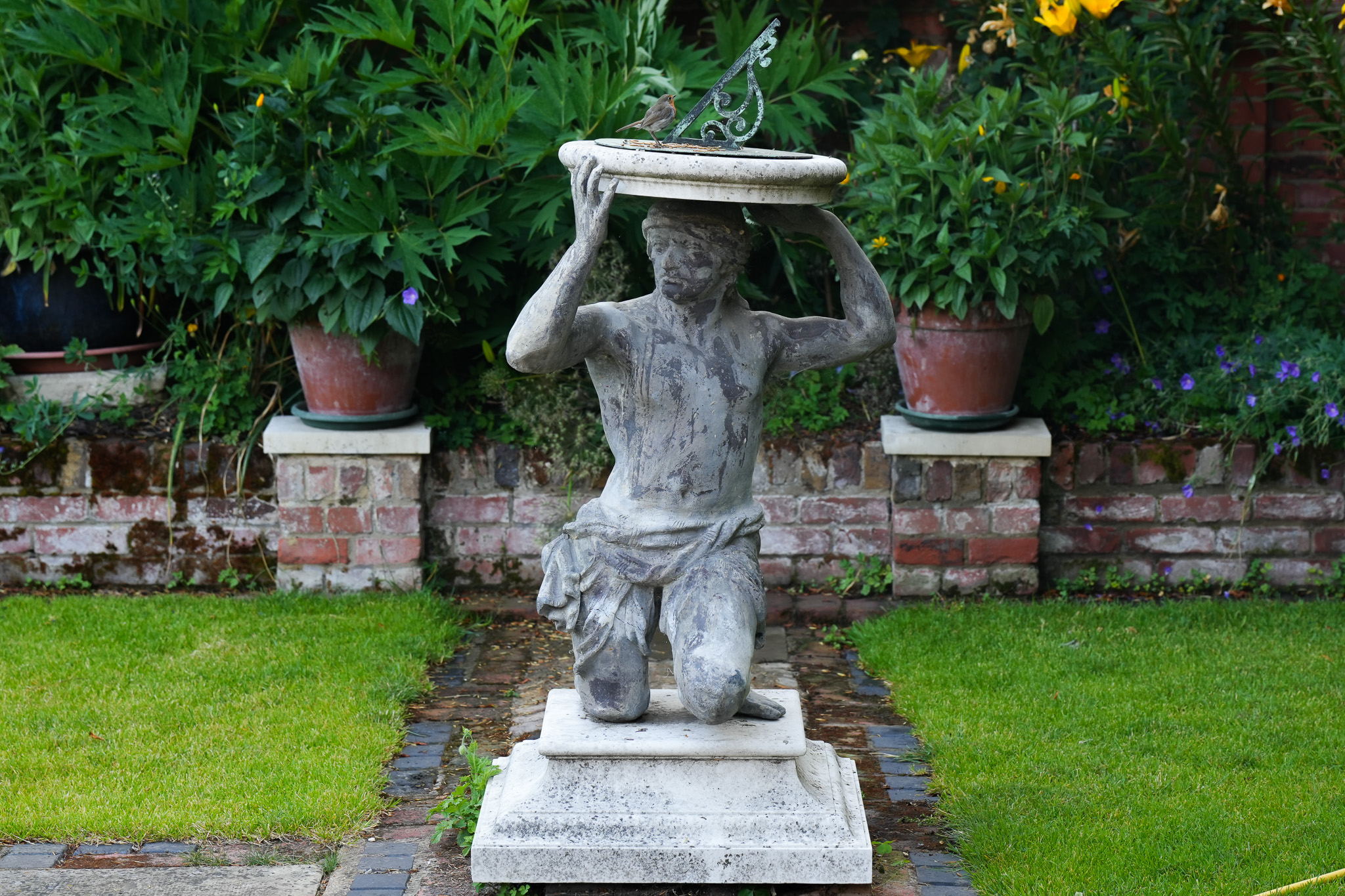 Landscape image on a kneeling indian statue on a stone plinth.